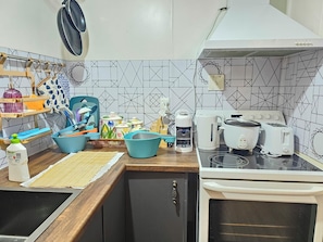 A kitchen with a stove, toaster, kettle, and various utensils and containers on the counter.