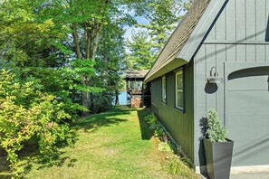 A house with a covered outdoor area, a wooden deck, and a small garden. - Lake Winnipesaukee Waterfront Sandy Beach 40 Ft Dock Sleeps 10 (Moultonborough)