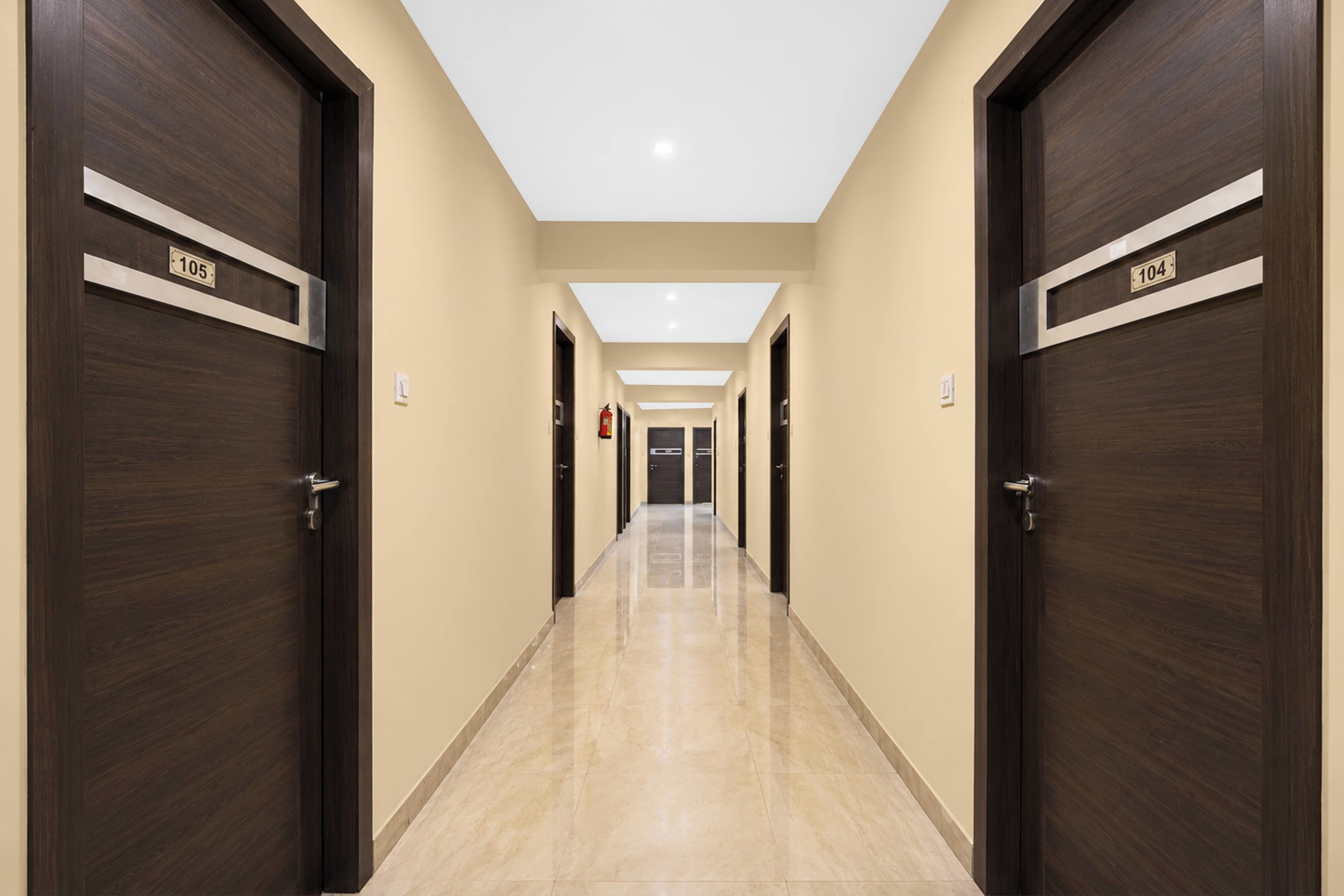 A hotel corridor with dark wooden doors, numbered 105 and 104, leading to rooms.