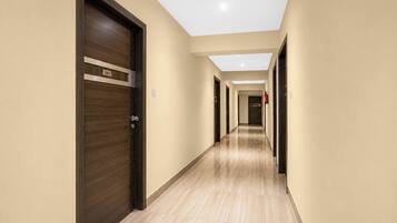 Un couloir d’hôtel avec des portes en bois, un sol carrelé et un plafond vitré.