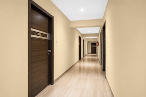 Un pasillo de hotel con puertas de madera, piso de baldosas y techo con tragaluces.