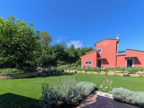Ein modernes, rotes Haus mit gepflegtem Rasen und Garten.