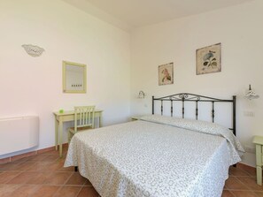 Een slaapkamer met een bed, een bureau, een stoel en een radiator.