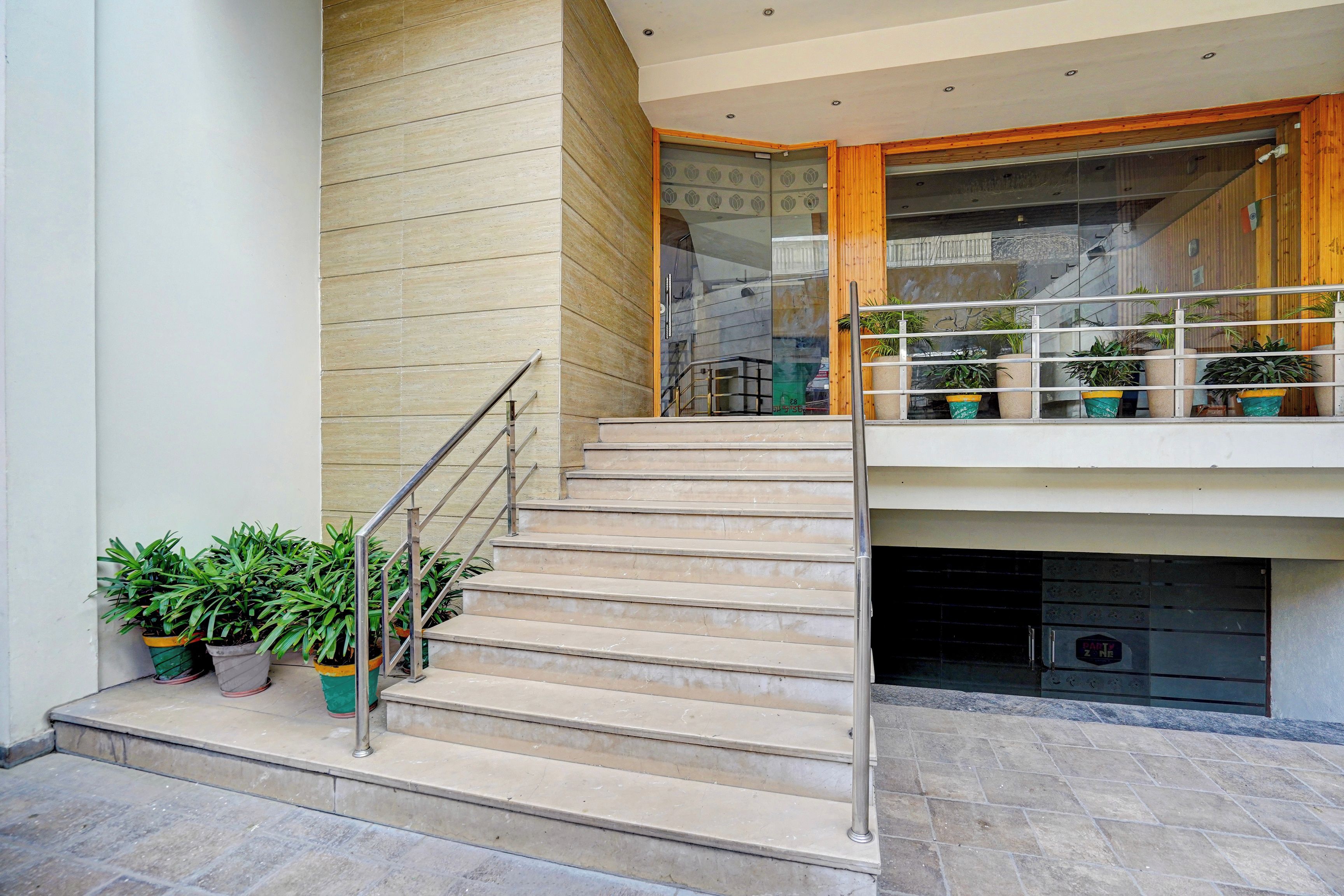 A staircase leading to a second-floor balcony with potted plants.