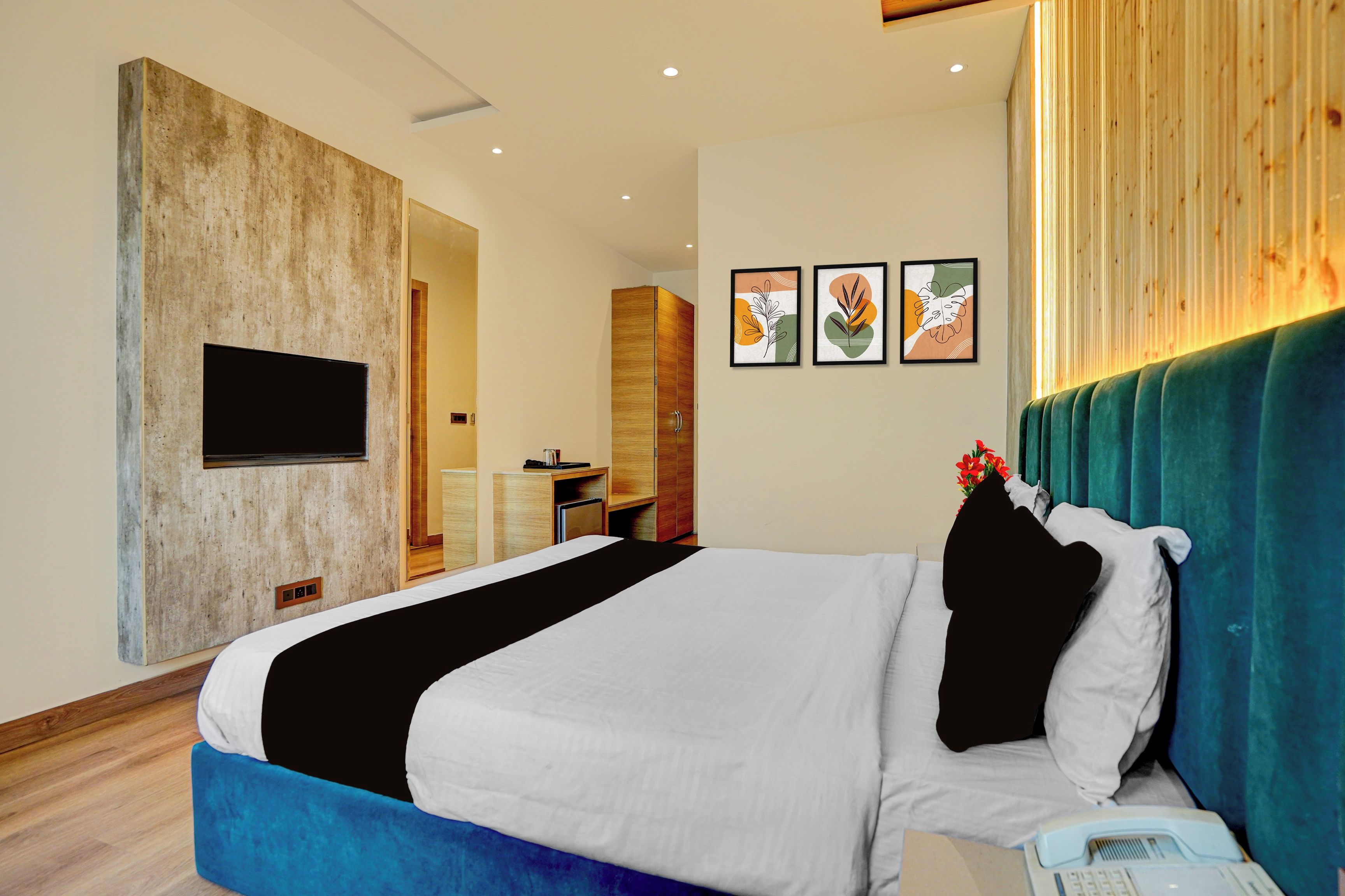 A modern hotel room with a large bed, a flat-screen TV mounted on the wall, and a wooden accent wall.