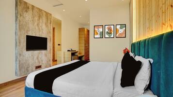A modern hotel room with a large bed, a flat-screen TV mounted on the wall, and a wooden accent wall.
