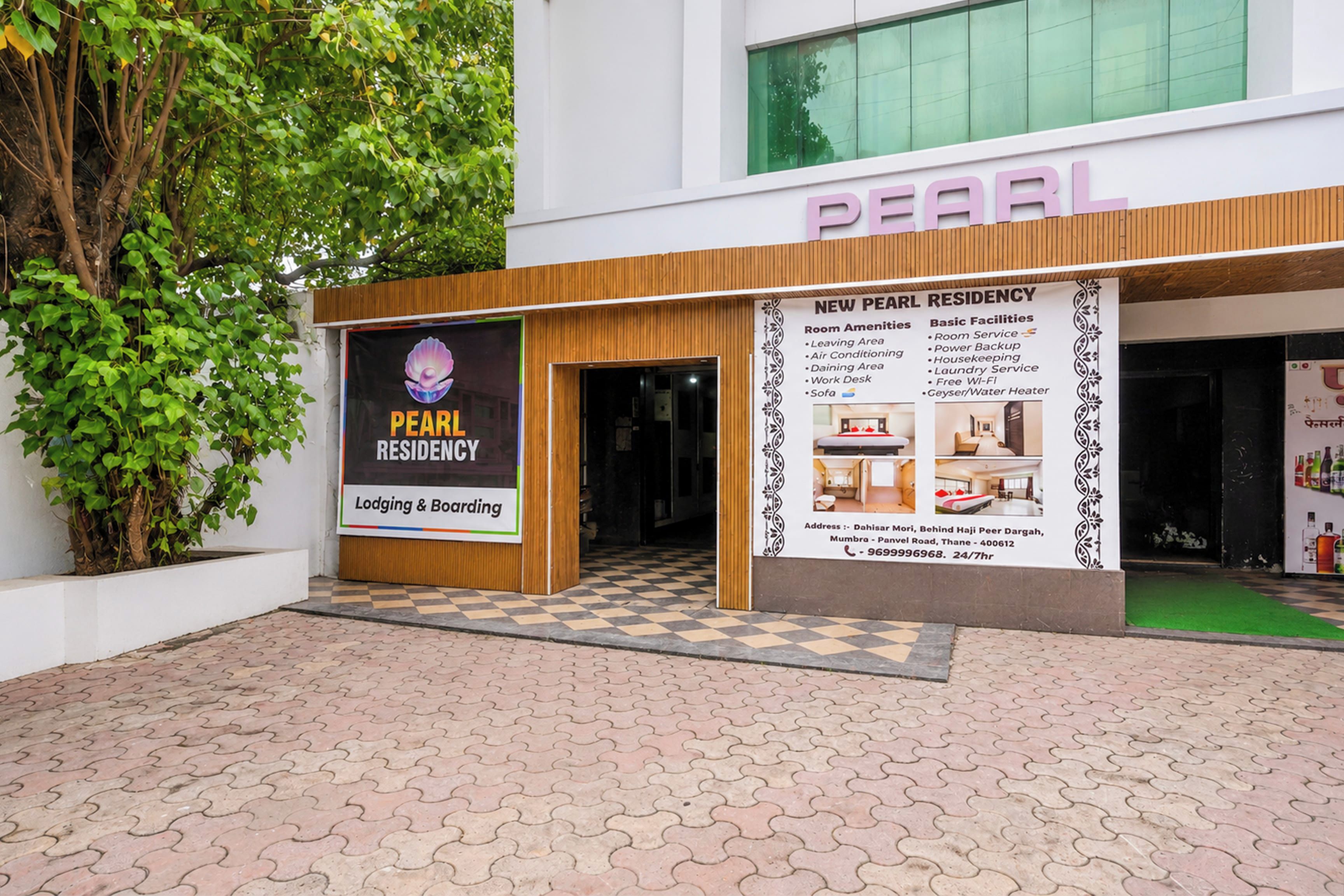 A Pearl Residency building with a checkered pavement in front, a signboard with amenities, and a large window above the entrance.