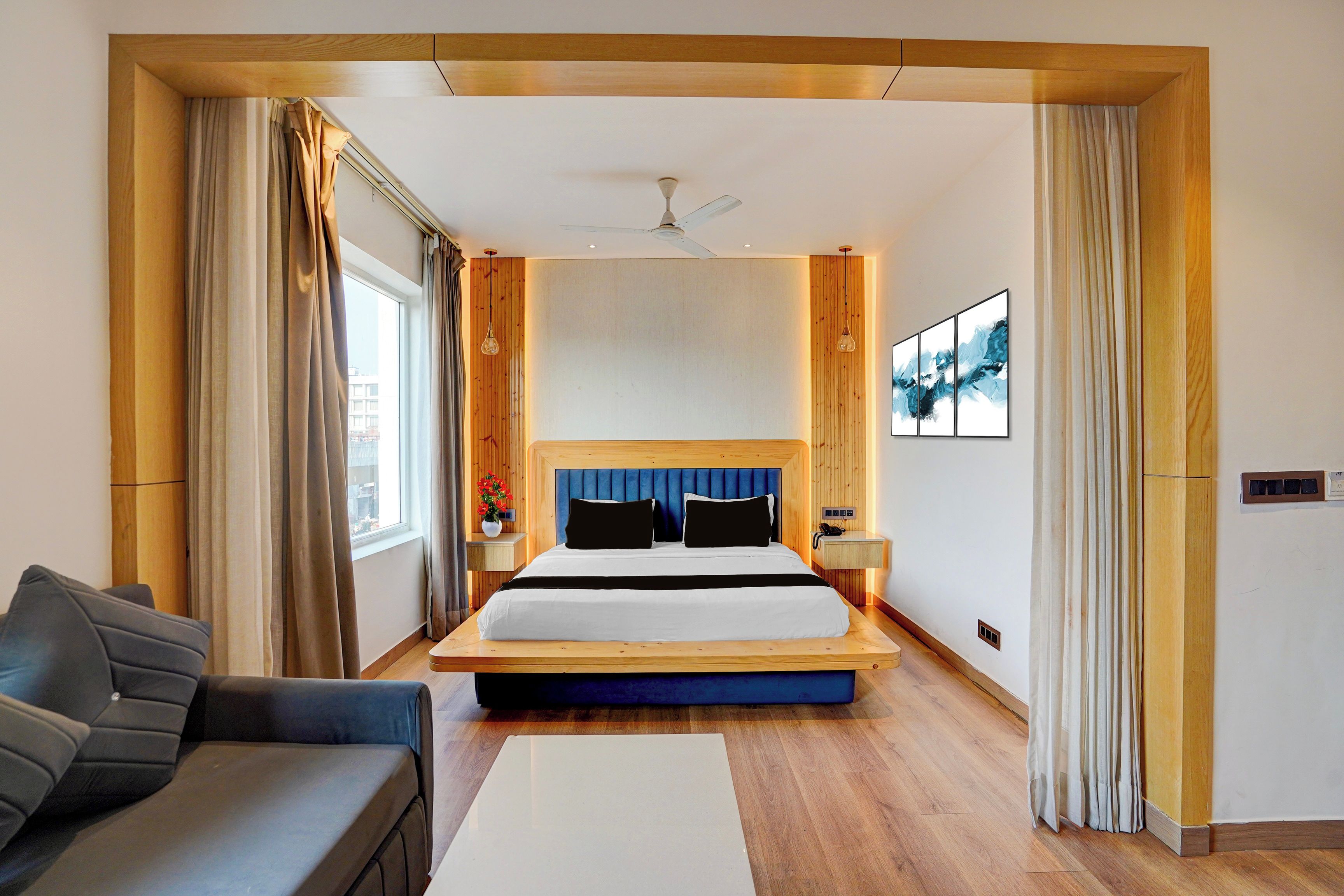 Ein Hotelzimmer mit einem großen Bett, einer Couch, einem Schreibtisch und Blick auf die Stadt.