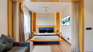 Ein Hotelzimmer mit einem großen Bett, einer Couch, einem Schreibtisch und Blick auf die Stadt.