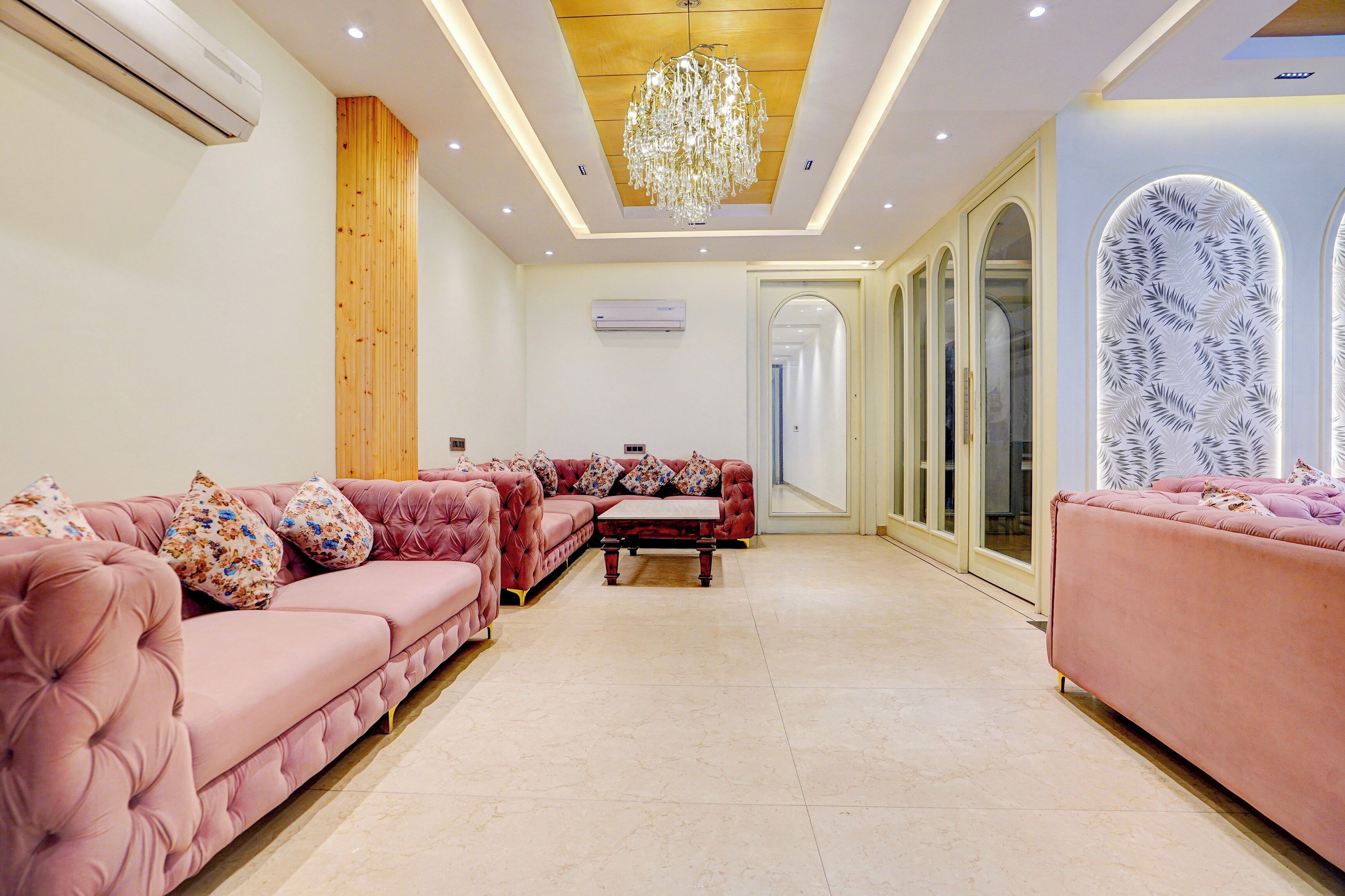 A spacious living room with a large sofa set, a chandelier, and a modern design.