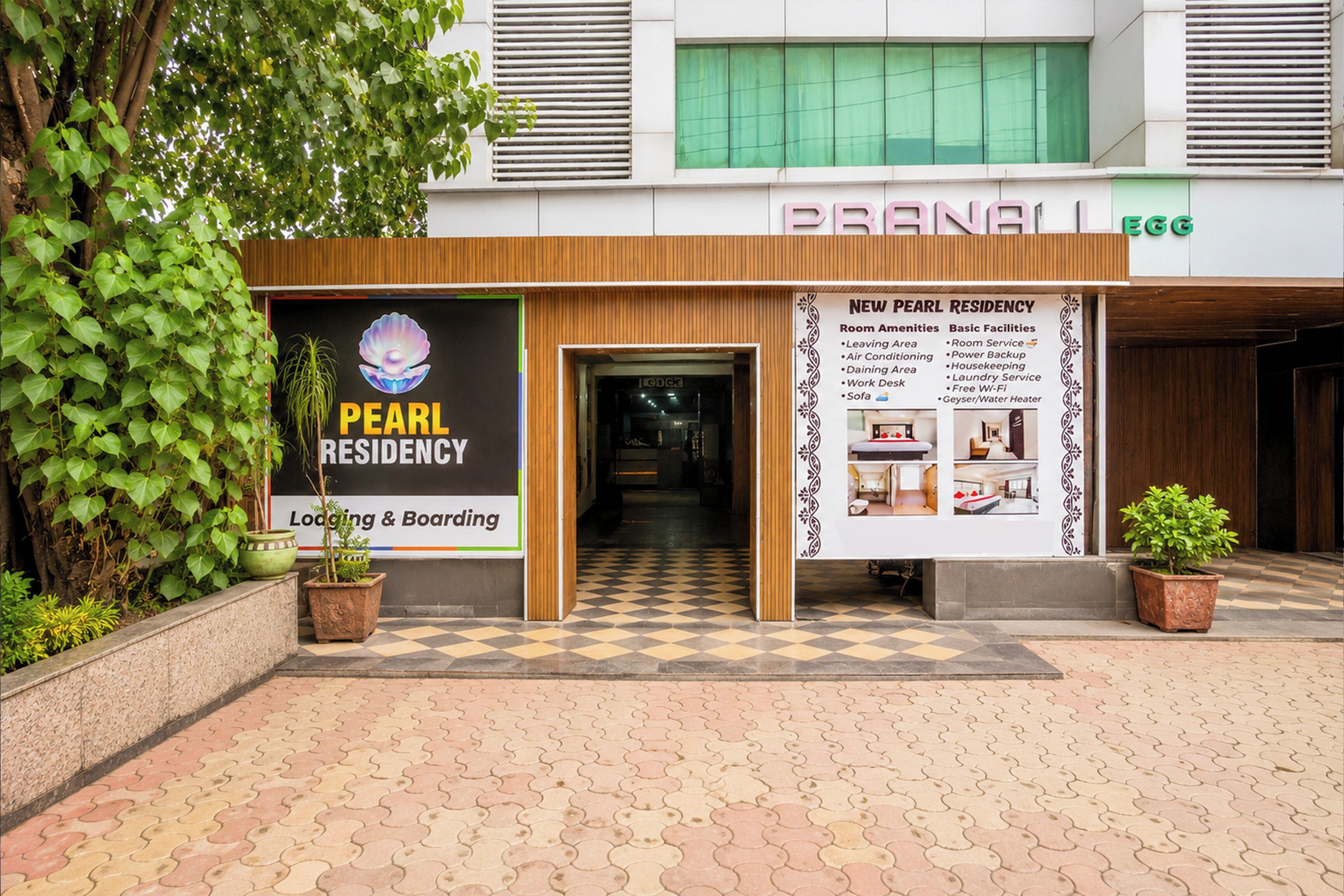 A building entrance with a sign for 'Pearl Residency' and a brochure detailing amenities and facilities.