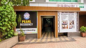 A hotel named 'Pearl Residency' with a signboard advertising room amenities and basic facilities.