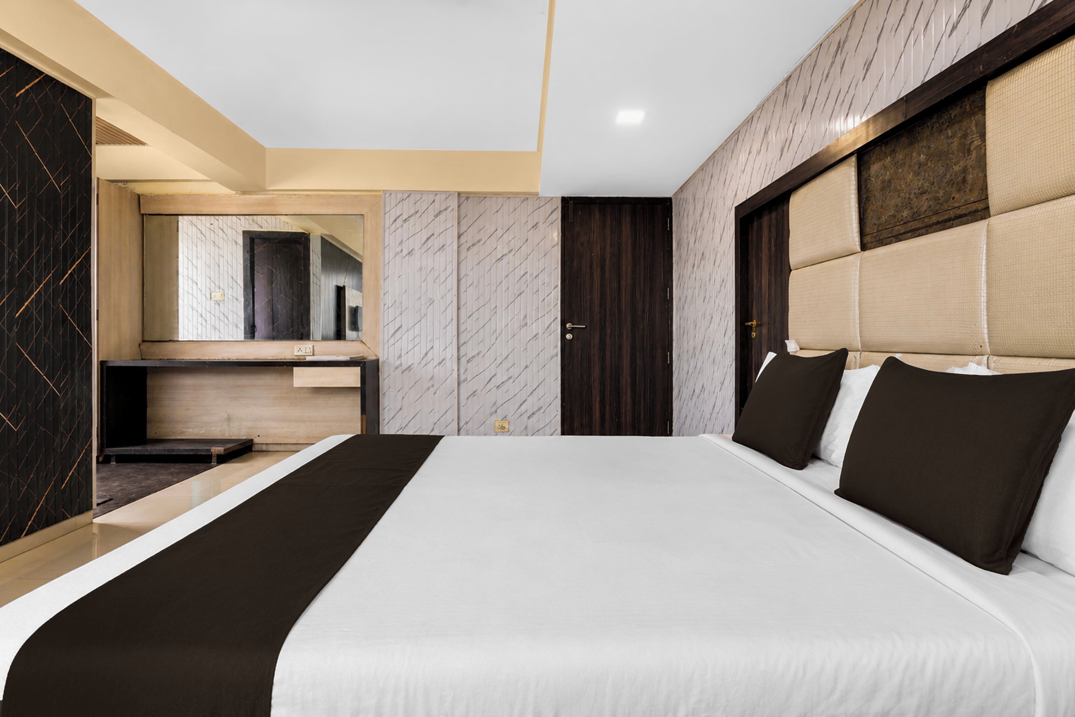 Et moderne hotelværelse med en stor seng, skrivebord og et spejl.