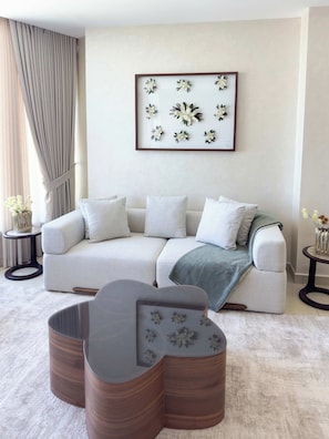 Un salon moderne avec un canapé d’angle, une table basse et une œuvre d’art florale encadrée accrochée au mur.