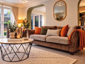 A cozy living room with a sofa, a round coffee table, and a large mirror. - Westend Parade (Gloucester)