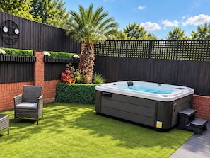 A backyard with a hot tub, a chair, and a wooden fence. - Westend Parade (Gloucester)