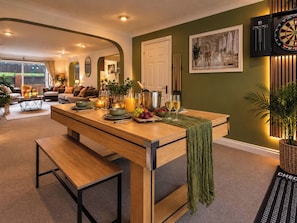 A dining area with a wooden table set for four, a bench, and a green throw draped over the table. - Westend Parade (Gloucester)