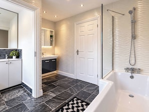 A modern bathroom with a bathtub, shower, and a vanity with a mirror. - Westend Parade (Gloucester)