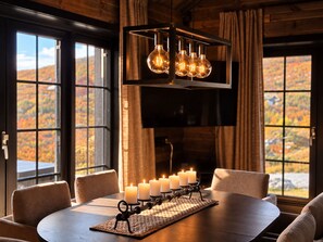 A dining area with a round table, six candles, and a modern light fixture. - Modern Alpine Living in Ustaoset (Hol)