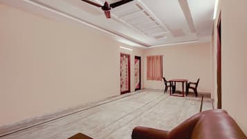 A room with a ceiling fan, a table with chairs, and a door with a decorative panel.
