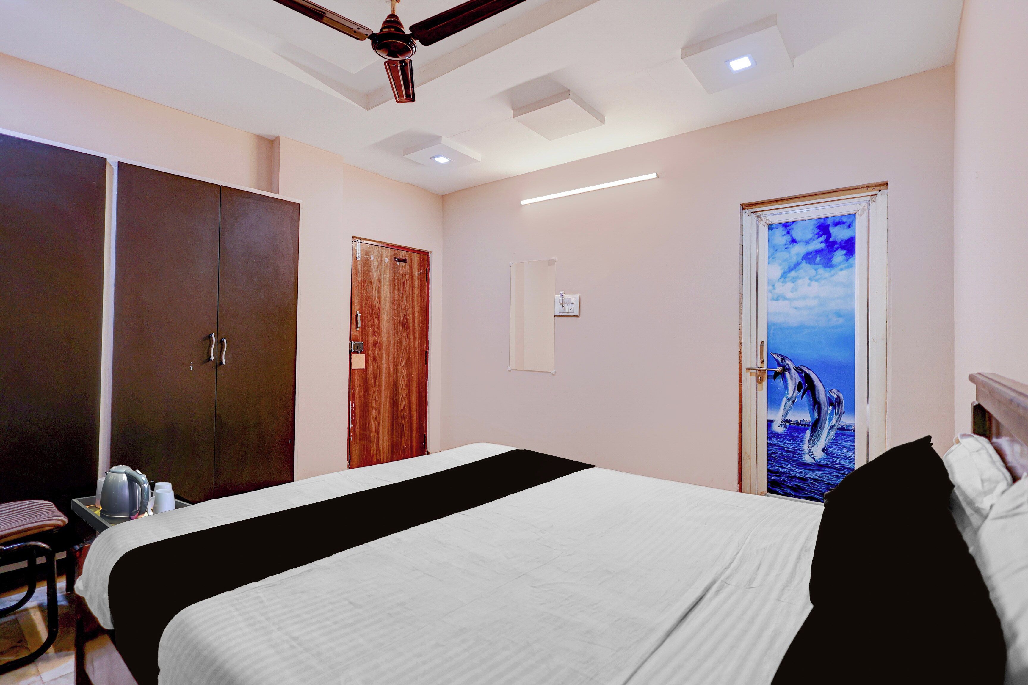 A hotel room with a bed, wardrobe, and a door with a dolphin mural.
