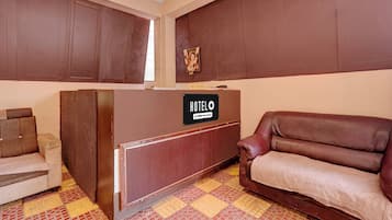 Un espace d’accueil avec un comptoir de réception portant l’inscription « HOTELO » et un canapé.