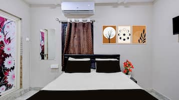 Un dormitorio con cama, aire acondicionado, espejo, ventana con cortinas y decoración en la pared.