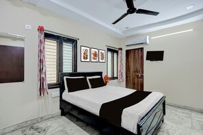 Quarto com cama, ventilador de teto, ar condicionado e televisão.