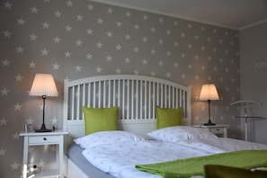 A bedroom with a bed, two nightstands, two lamps, and a wall with star patterns.