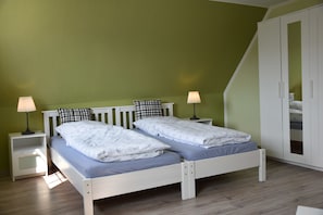 A twin bed with a headboard, two bedside tables with lamps, and a wardrobe with a mirror.