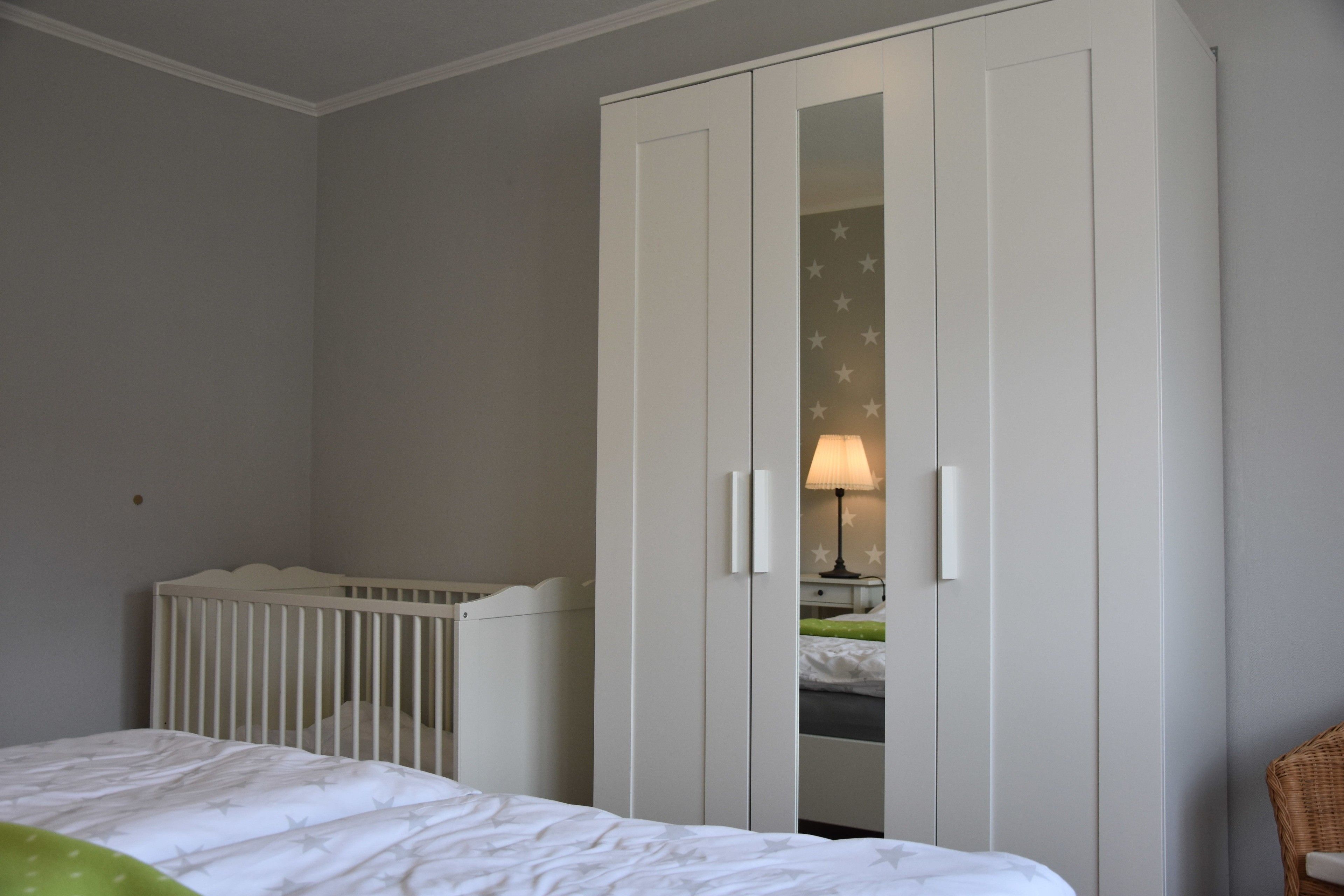 Ein Schlafzimmer mit einem Babybett, einem Kleiderschrank und einem Bett.