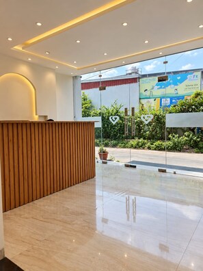A modern reception area with a wooden reception desk, a glass partition, and a view of the street outside. - Silvotel SmartBy Bizzgrow Hotels (Indore)