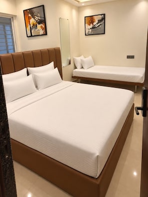 A hotel room with a large bed, a smaller bed, a mirror, and two paintings on the wall. - Silvotel SmartBy Bizzgrow Hotels (Indore)