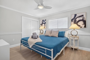 A bedroom with a bed, a ceiling fan, a window with blinds, and artwork on the walls. - Pool, Hot Tub & Water Access | Cape Coral Home (Cape Coral)