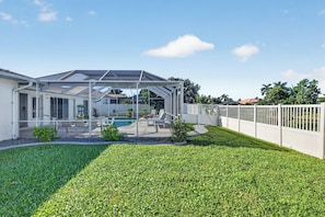 A house with a covered patio, a swimming pool, and a well-maintained lawn. - Pool, Hot Tub & Water Access | Cape Coral Home (Cape Coral)