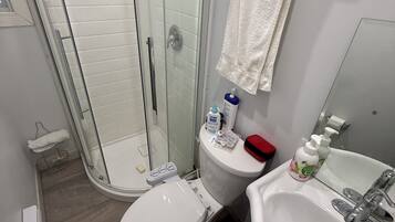 Une salle de bain avec une douche à parois de verre, des toilettes, un lavabo et des articles de toilette.