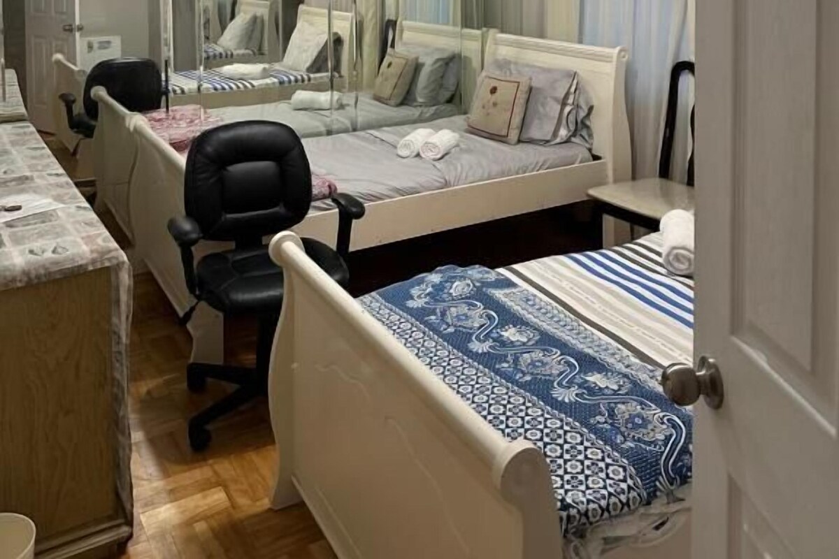 A bedroom with a bed, a chair, a desk, and a mirror.