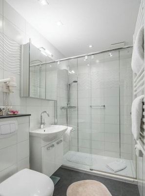 Ein modernes Badezimmer mit Duschkabine aus Glas, einem weißen Waschbecken und einem großen Spiegel.