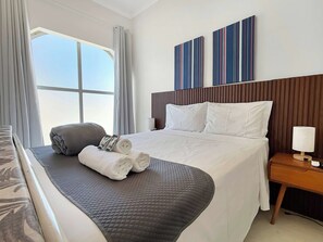 A hotel room with a large bed, a bedside table with a lamp, and a window with curtains.