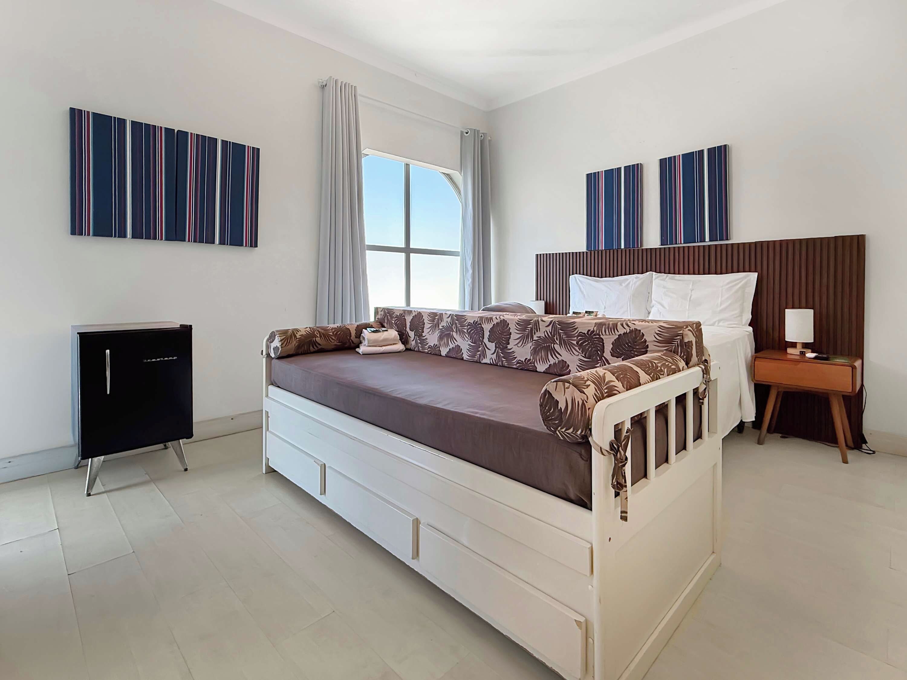 A modern bedroom with a bed, bedside table, lamp, and artwork on the walls.