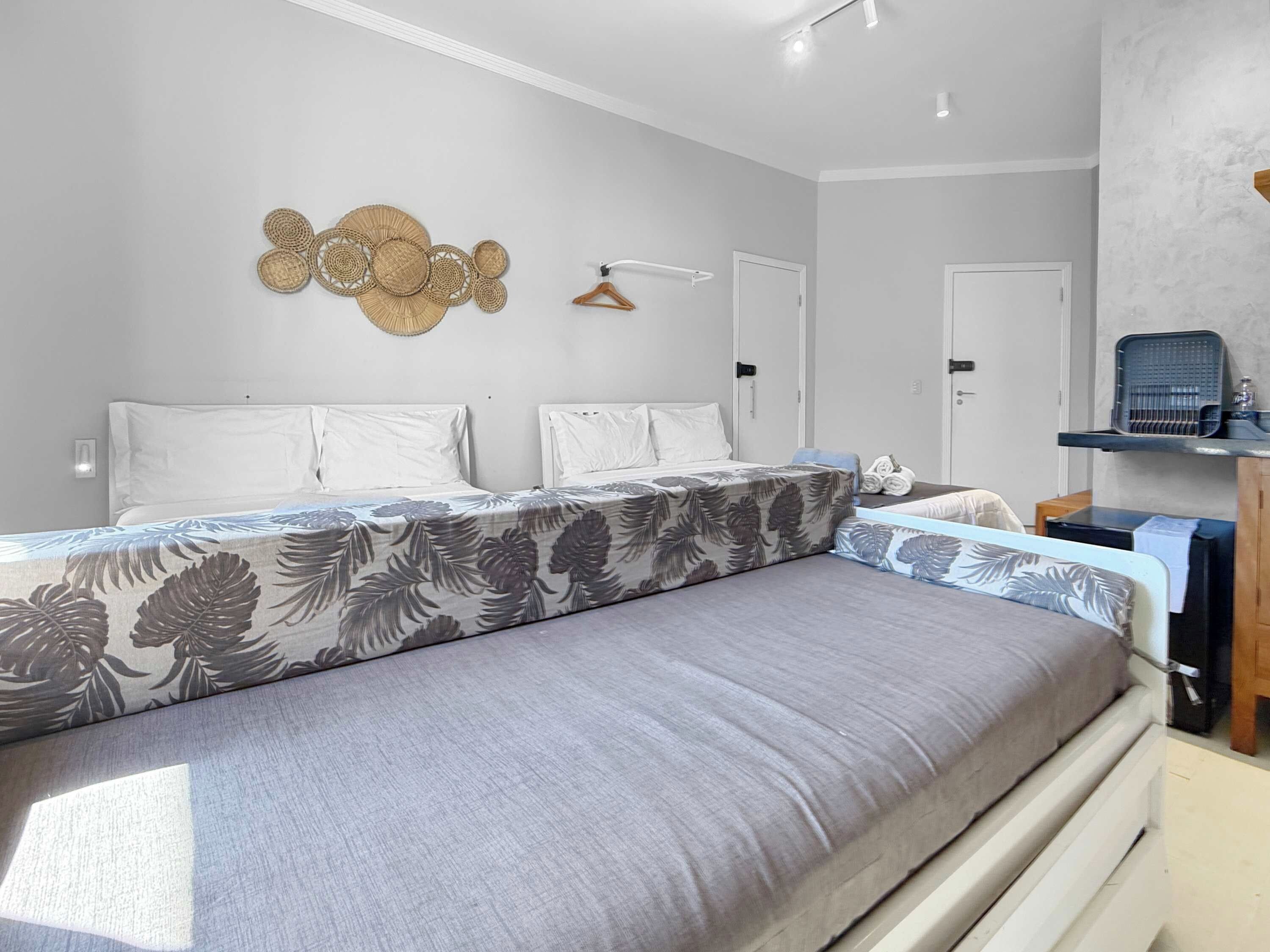 A modern bedroom with a large bed, a bedside table, a hanging light, and a wall-mounted decorative item.