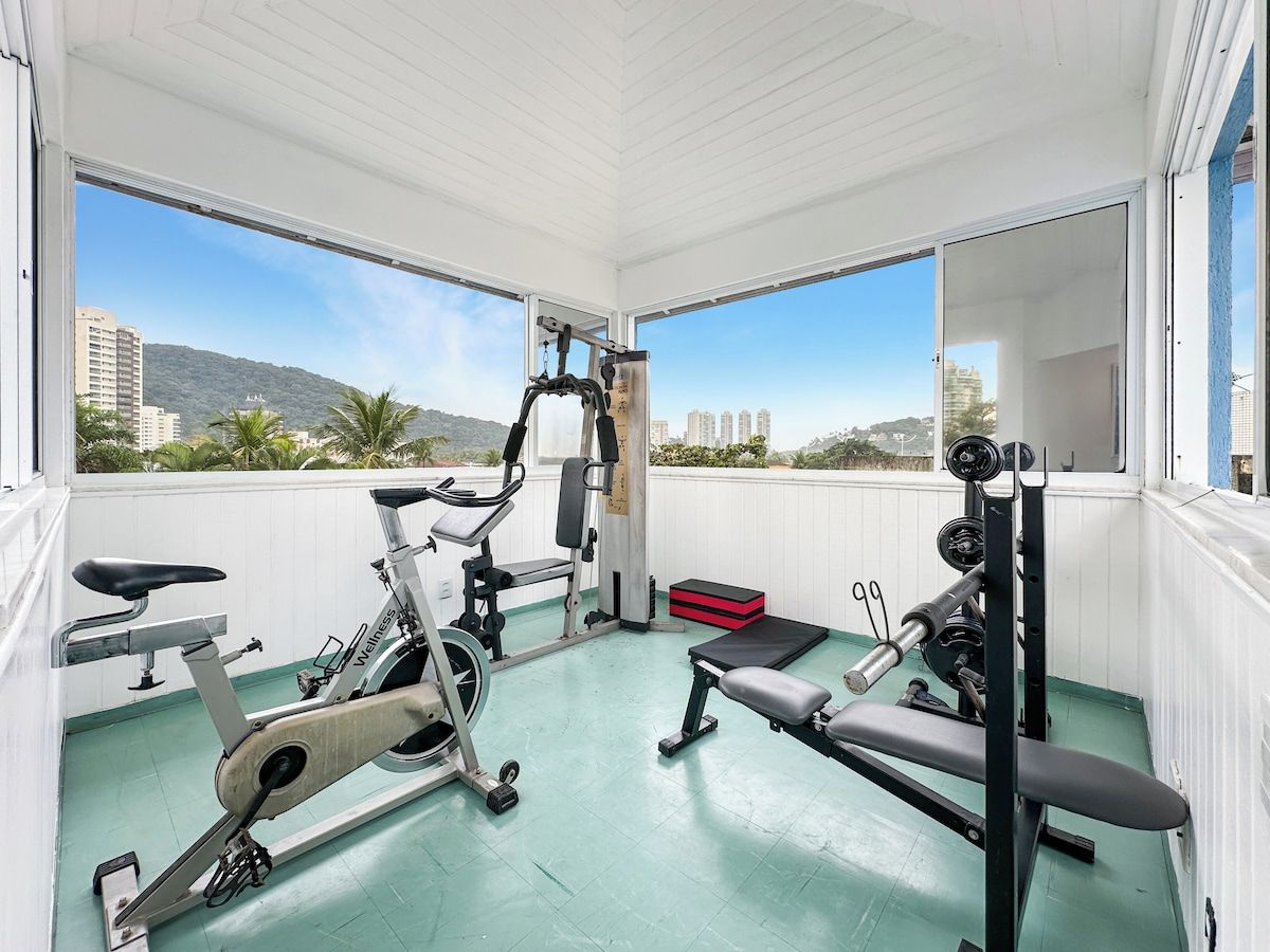 A gym with exercise equipment, large windows, and a view of buildings and hills.
