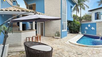 A poolside area with a stone floor, outdoor seating, and a pool with a blue border.