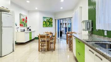 Una cocina moderna con isla central, armarios blancos y salpicadero verde.
