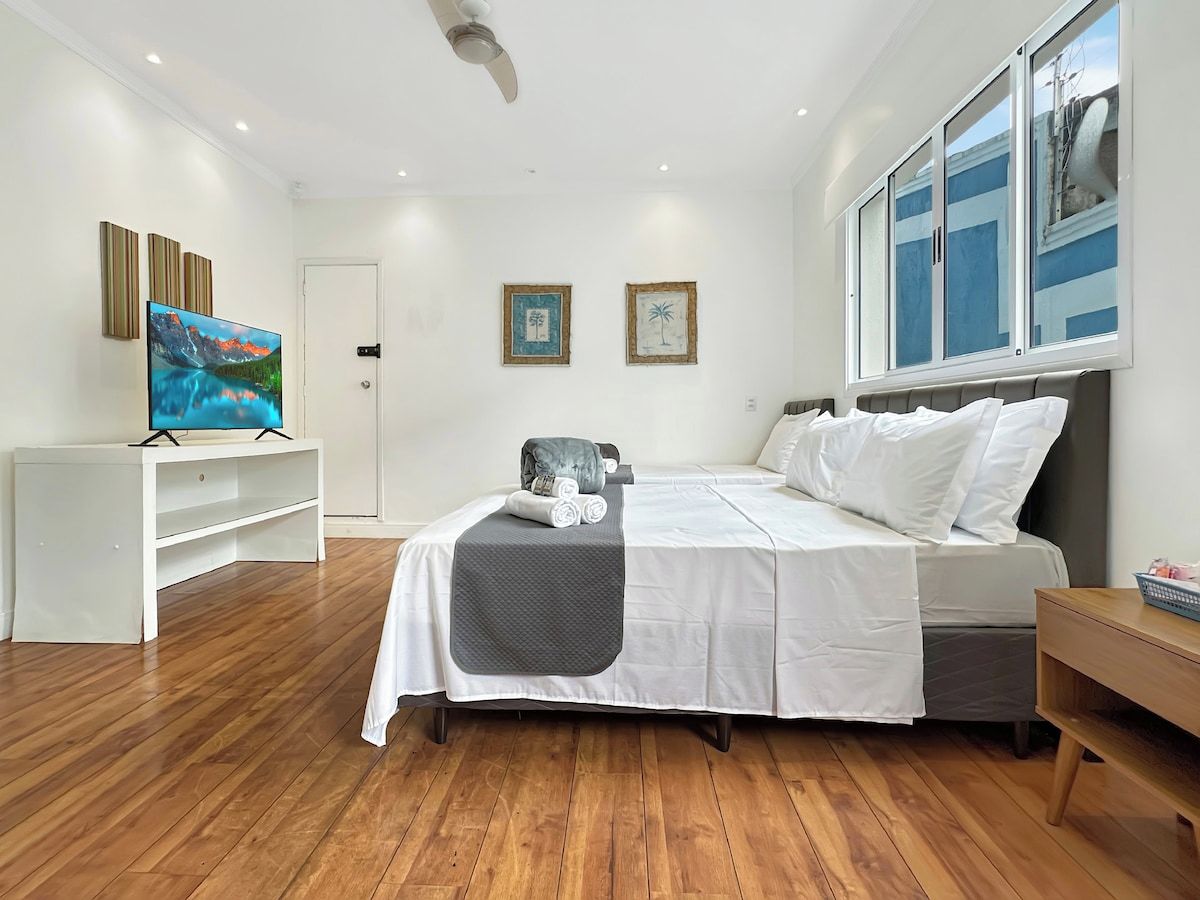 A bedroom with a bed, a TV, and artwork on the walls.