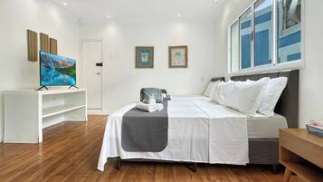 A bedroom with a bed, a TV, and artwork on the walls.