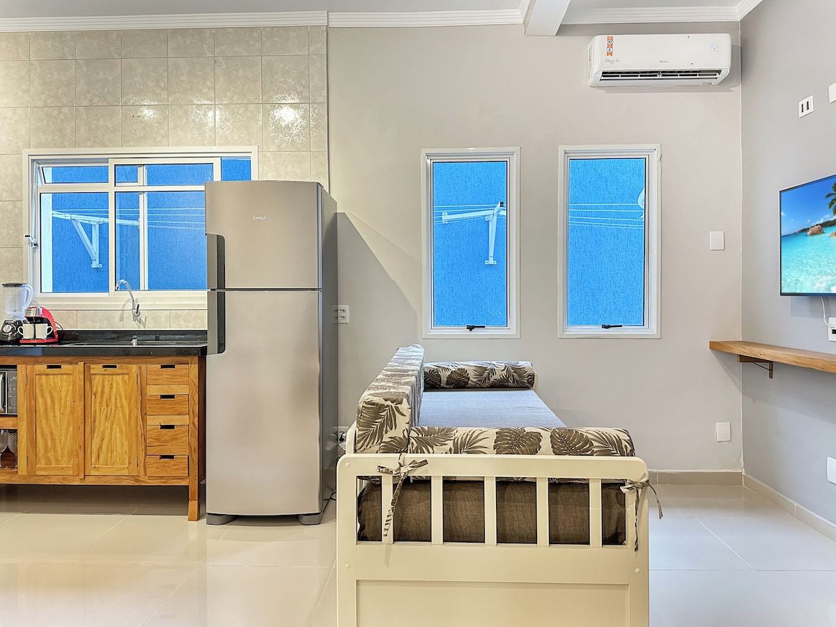 A modern kitchen with a refrigerator, wooden cabinets, and a countertop with a coffee maker.