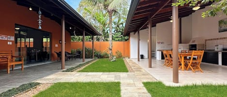 A covered outdoor area with a patio, seating, and a palm tree.