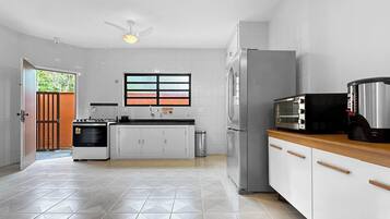 A modern kitchen with white cabinets, a stainless steel refrigerator, a built-in oven, and a microwave.