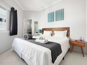 Une chambre d’hôtel avec un lit, une table de chevet, un miroir et vue sur la salle de bain.